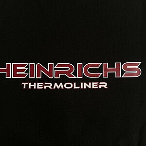 Heinrichs Thermoliner Brustlogo – Detailfoto des kleinen roten Schriftzugs auf schwarzem Hoodie