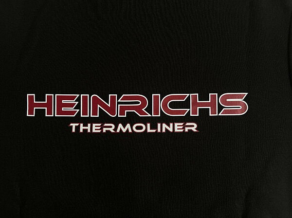 Heinrichs Thermoliner Brustlogo – Detailfoto des kleinen roten Schriftzugs auf schwarzem Hoodie