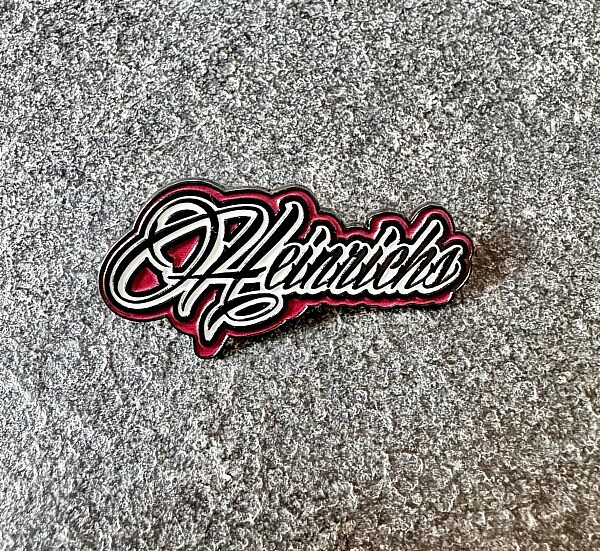 Metall-Pin mit „Heinrichs“-Logo-Schriftzug in Schwarz-Rot, ideal für Trucker, Fans und Sammler – Hängerzug-Style to go.
