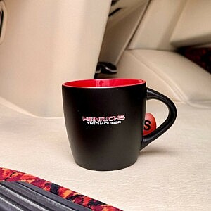 Schwarze Tasse mit rotem Innenleben und dem „Heinrichs Thermoliner“-Logo – der perfekte Becher für Truck-Fans mit Geschmack.