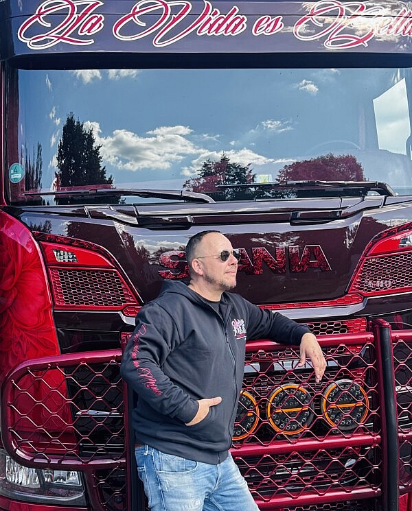 Hoodiejacke von Heinrichs Thermoliner mit Frontprint und Ärmel-Schriftzug „Construido por los Mejores“ vor dem Truck „La Vida es Bella“.