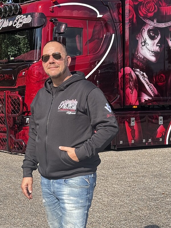 Heinrichs Thermoliner Hoodiejacke „La Vida es Bella“ mit Frontlogo und linkem Ärmel-Stick, getragen vor dem gleichnamigen Showtruck.